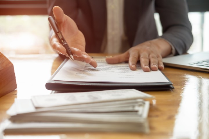 A businessperson reviewing and signing important paperwork at a desk