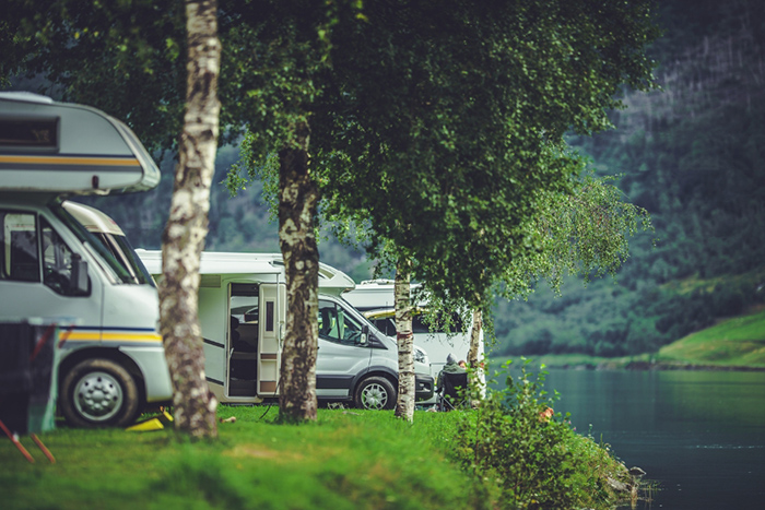 a serene RV park bathed in sunlight, with several recreational vehicles of various sizes and designs parked in designated spots